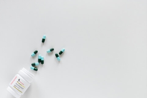 A handful of capsules spilling out from a medicine bottle